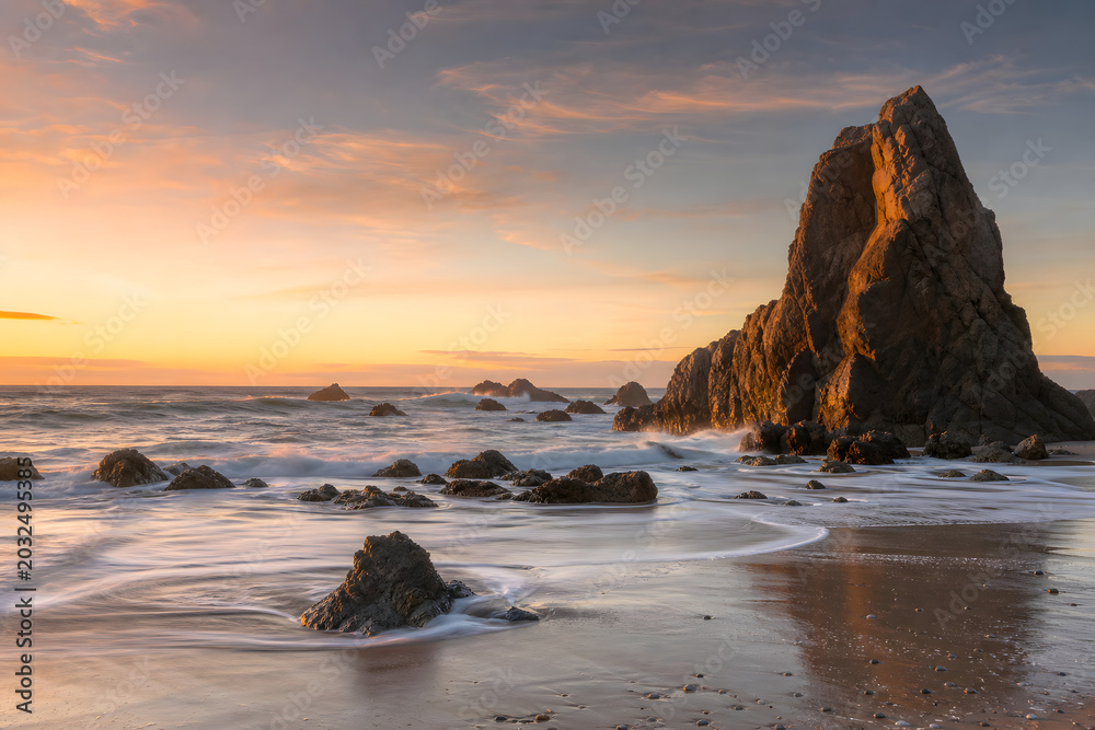 Naklejka premium Golden Waves Around Towering Coastal Rock Formations