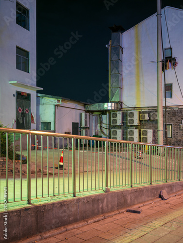 Vászonkép Empty street corner with metal fence illuminated by green light at night
