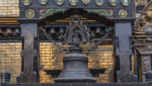 Fotografie A large ancient black bell is suspended on chains