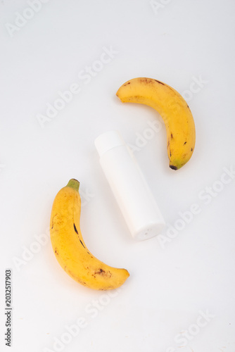 Two ripe bananas and a white bottle on the white background.