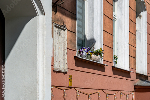 Tableau sur toile Fragment of an orange-pink tenement facade in bright sunlight, featuring a white