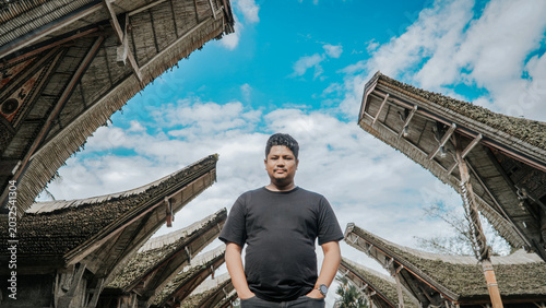 Foto Man stands beneath the traditional Tongkonan roofs of the Torajan ethnic house