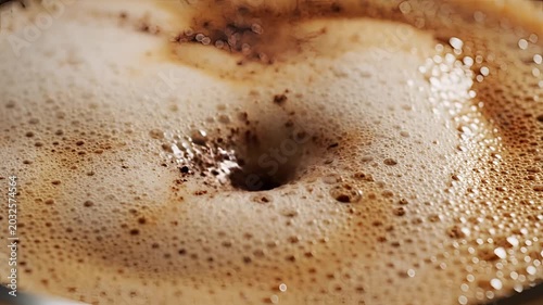 Closeup of hot coffee being poured creating a swirling vortex and foam.