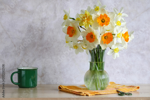 Bouquet of garden daffodils in a glass vase on the table, spring still life