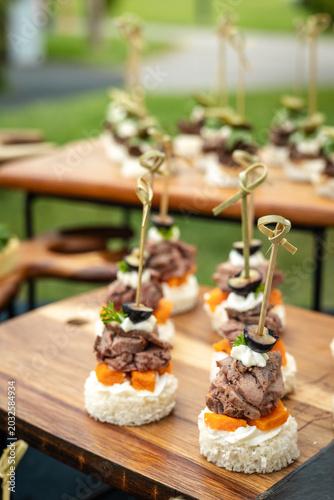 Elegant bite-sized appetizers with meat and olives arranged on wooden trays for a banquet