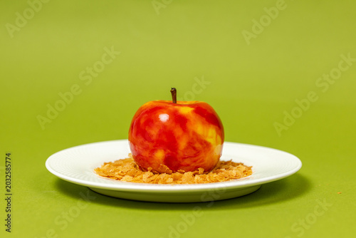 Glazed red and yellow mousse cake crafted as a realistic apple served over crispy flakes.