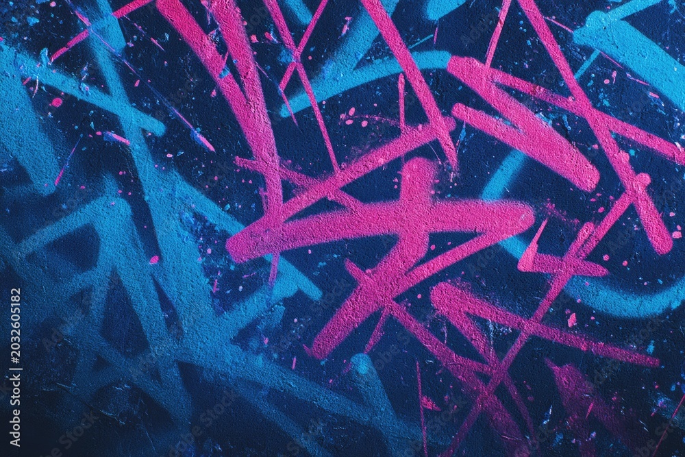 Fototapeta premium Abstract graffiti art with intersecting neon pink and blue spray-painted lines on a dark background