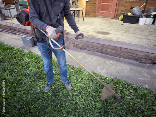 Grass string trimmer cutting weeds in residential backyard garden