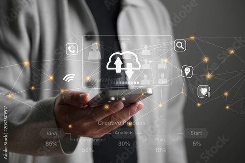 Business man holding smart phone to download file with glowing digital quality excellence of high technology marketting concept
