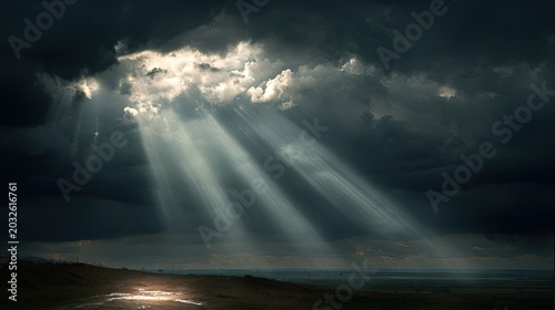 Dramatic cloudy sky with sunlight rays breaking through dark storm clouds over a coastal landscape