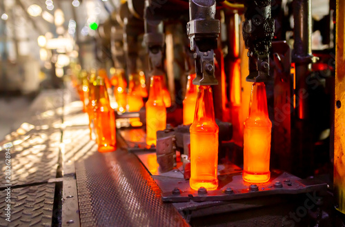 Glass factory, production of glass containers. Molten glass is blown into molds. Robotics in industry. Modern technologies, robotic machines produce products. Technological work at the plant.