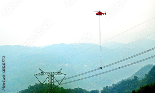 Helicopter Carries High Voltage Transmission Lines Over Mountainous Area