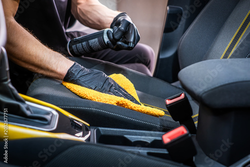 Cleaner hands cleaning car seat with yellow cloth and spray, interior car wash and vehicle cleaning concept

