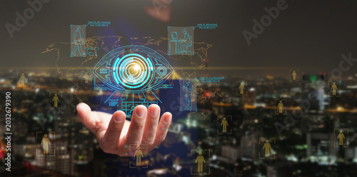 Hand holding glowing AI surveillance eye over city skyline and world map. Surveillance state, people tracking, facial recognition, privacy risk, global monitoring, data security, and digital control.