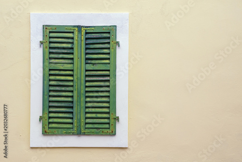 Building facade with window covered with old green wooden shutters. Copy space