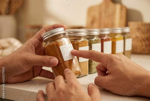 Blind Person Reading Braille Label on Spice Jar in Kitchen