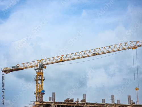 Tableau sur toile Heavy duty industrial tower crane lifting materials above a concrete building si