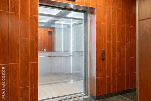 Glass elevator in a modern building with wood paneling
