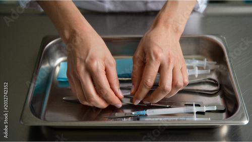 Schilderij op canvas Surgical tools on a metal tray being organized for medical procedure