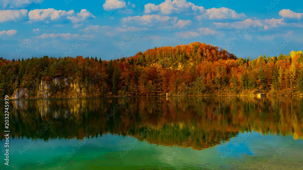 Obraz premium Panoramic view of sunset scene with the Alpsee lake in Autumn trees season and Bavaria Alps in background