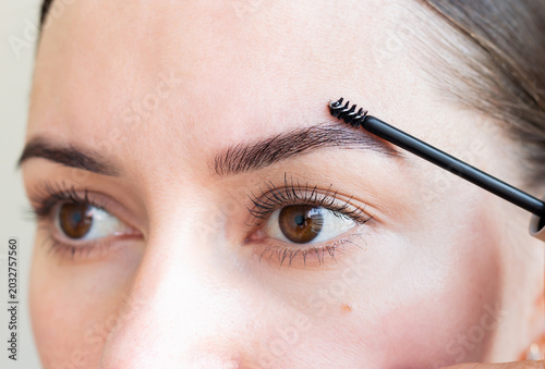 Foto Young woman combing her eyebrows with a brush, making a beautiful shape