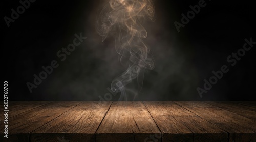 Wooden table surface in dark room with rising smoke or steam, atmospheric mood.
