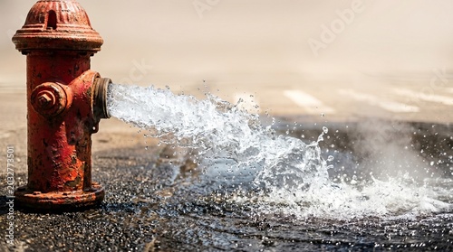 Close perspective of an Open Fire Hydrant Street releasing water onto the pavement. Designed for municipal infrastructure blogs, emergency services and public relief ads.