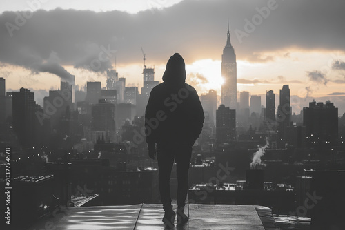 Person on roof gazes at city below.