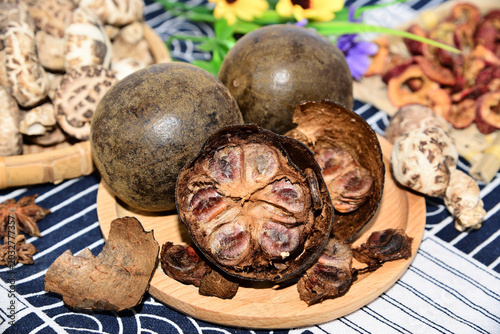 Dried monk fruit and herbal ingredients on wooden plate