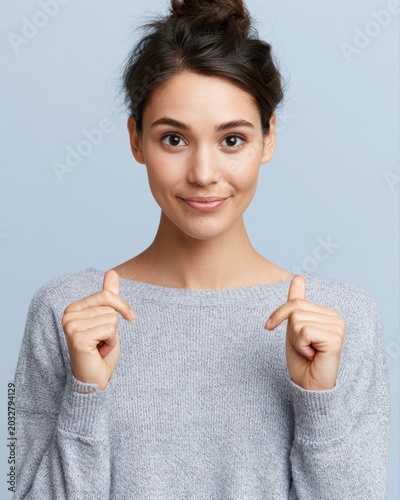 Young woman crossing fingers hopefully and smiling nervously