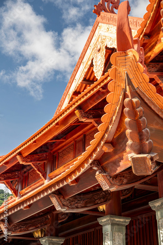 Photography Extreme close-up of richly detailed golden and red carved wooden temple eaves at the Ho Chi Minh memorial in Vietnam