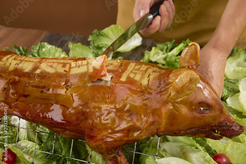 Foto Roast suckling pig being carved on lettuce garnish