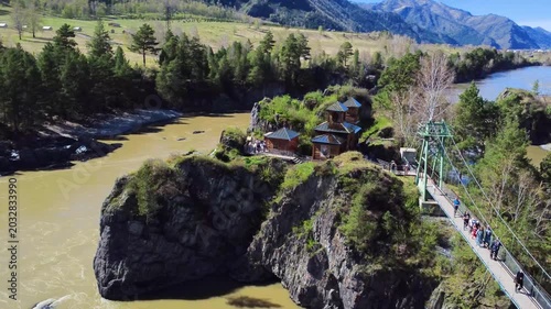 Floating Church Island. Elevated Chapel Resting Amidst Steep Rocky Islet Near Bridge. An Airborne Religious Building Situated Atop Rough Island Terrain Adjacent To Suspension Span And Crossing