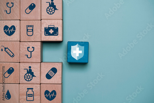 Foto Healthcare insurance and medical protection concept with wooden blocks showing hospital, vaccine, syringe and wellness icons beside shield symbol