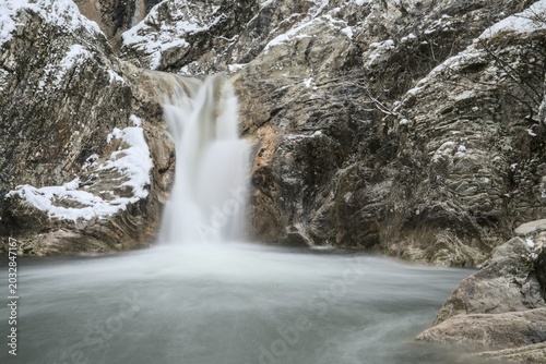 Принти на полотні A detailed long exposure shot of a mountain waterfall cascading over frozen, icy rocks in winter