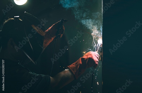 Photos Under the glow of a soft light, a dedicated welder focuses intently on joining metal pieces