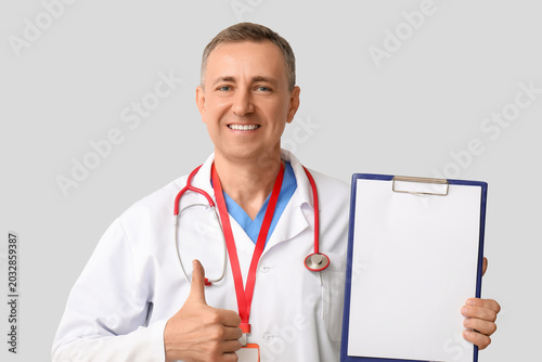 Mature doctor with clipboar...