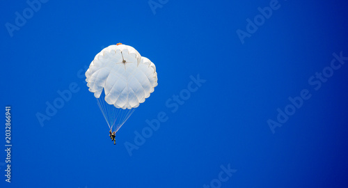 Skydiving. Flying parachutists against the background of the blue sky and mountains. Extreme sport and entertainment.