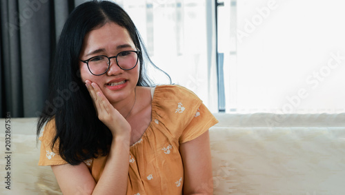 Foto Young Asian woman was experiencing oral health problems specifically tooth decay displayed pained expression suffering from severe toothache jaw pain and headache simultaneously