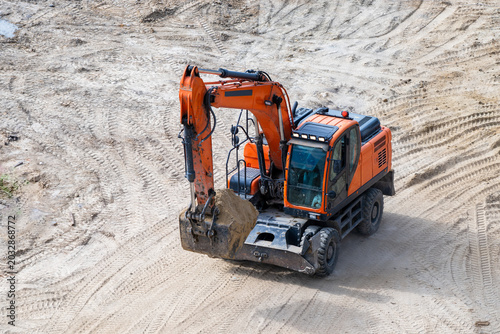 Foto a bright orange wheeled excavator maneuvering across a heavily tracked sandy construction site