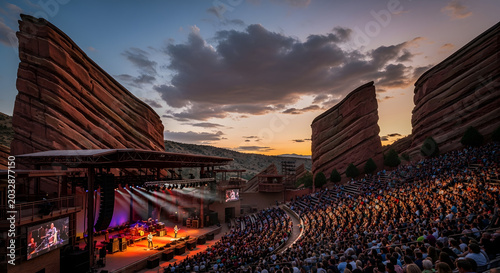 Concert event with large crowd watching live music performance on stage at outdoor amphitheater during sunset