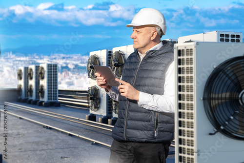 HVAC engineer inspects rooftop air conditioners, climate system maintenance and building service