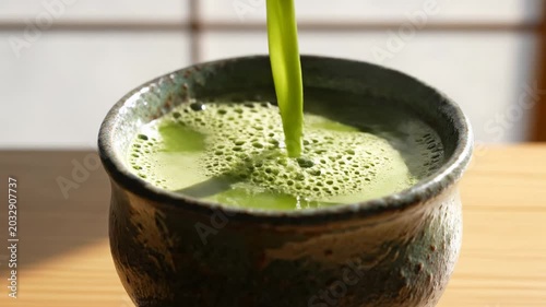 Pouring green matcha tea into ceramic bowl