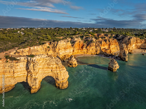 Aerial view of Praia da Marinha beach in Algarve, Portugal, with ocean cliffs, sea stacks and clear Atlantic water.