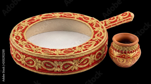 Ornate red and gold gota patti decorated sieve for Karva Chauth moon sighting ritual.