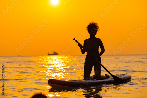 Bild auf Leinwand Woman Paddleboarding Silhouette at Golden Sunset Sea