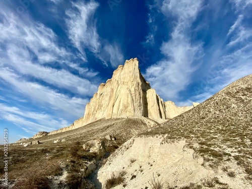 White limestone cliff under deep blue sky with wispy clouds
