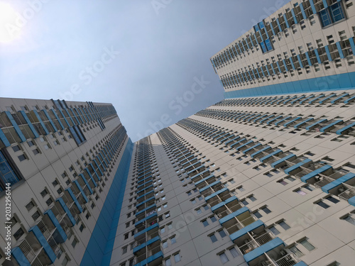 Low-angle shot of two tall, modern office buildings with blue accents against a clear blue sky.