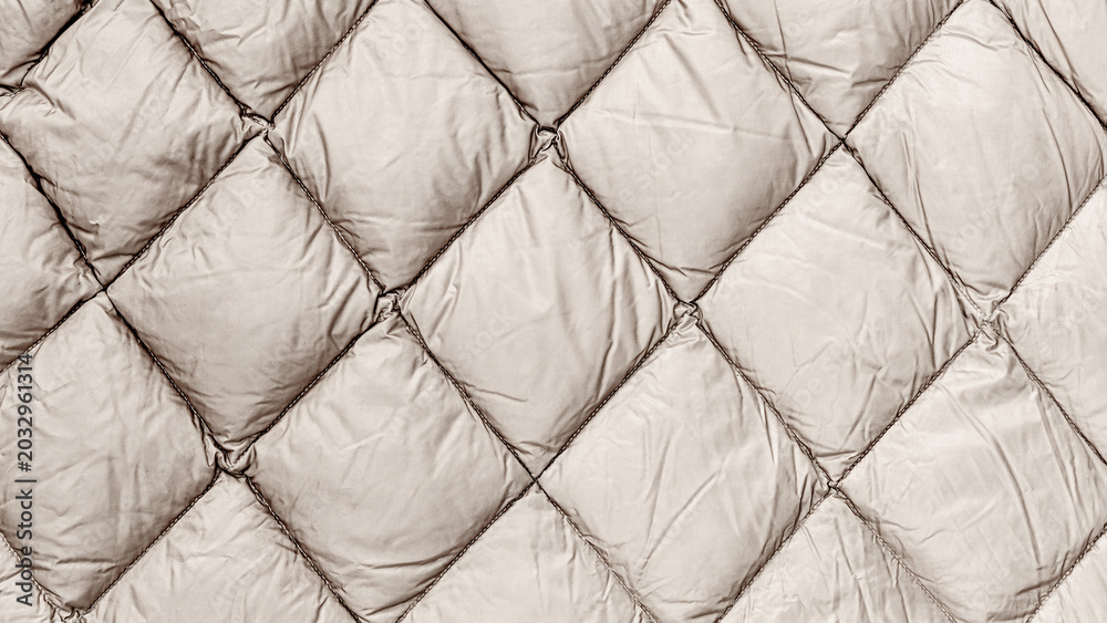 Naklejka premium Quilted fabric in neutral color displayed on a flat surface for review by a textile enthusiast or designer