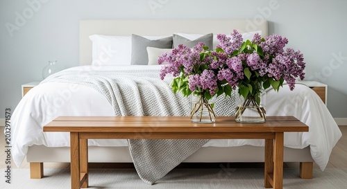 Minimalist bedroom with fresh lilac flowers on wooden bench.